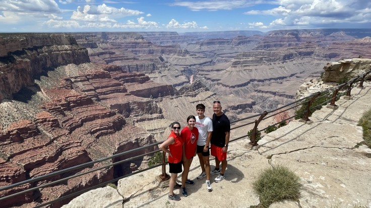 A family of four poses at a viewpoint overlooking the Grand Canyon in Grand Canyon National Park