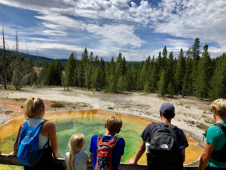 A family looks at a hot spring with many colors in Yellowstone National park